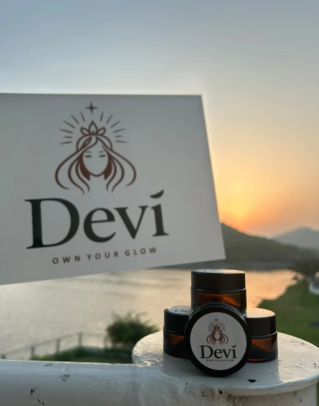 Devī logo card beside jars of Shakti balm at sunset in Udaipur